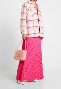 Ruudutettu vaaleanpunainen ja valkoinen takki, kirkkaan vaaleanpunainen maxi-hame, pastelliväri vaaleanpunainen laukku tähtikoristeilla ja valkoiset teräväkärkiset kengät.