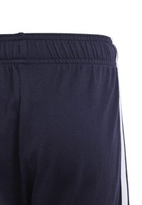 Navy athletic pants featuring a soft texture, elastic waistband, and white side stripes for added detail.