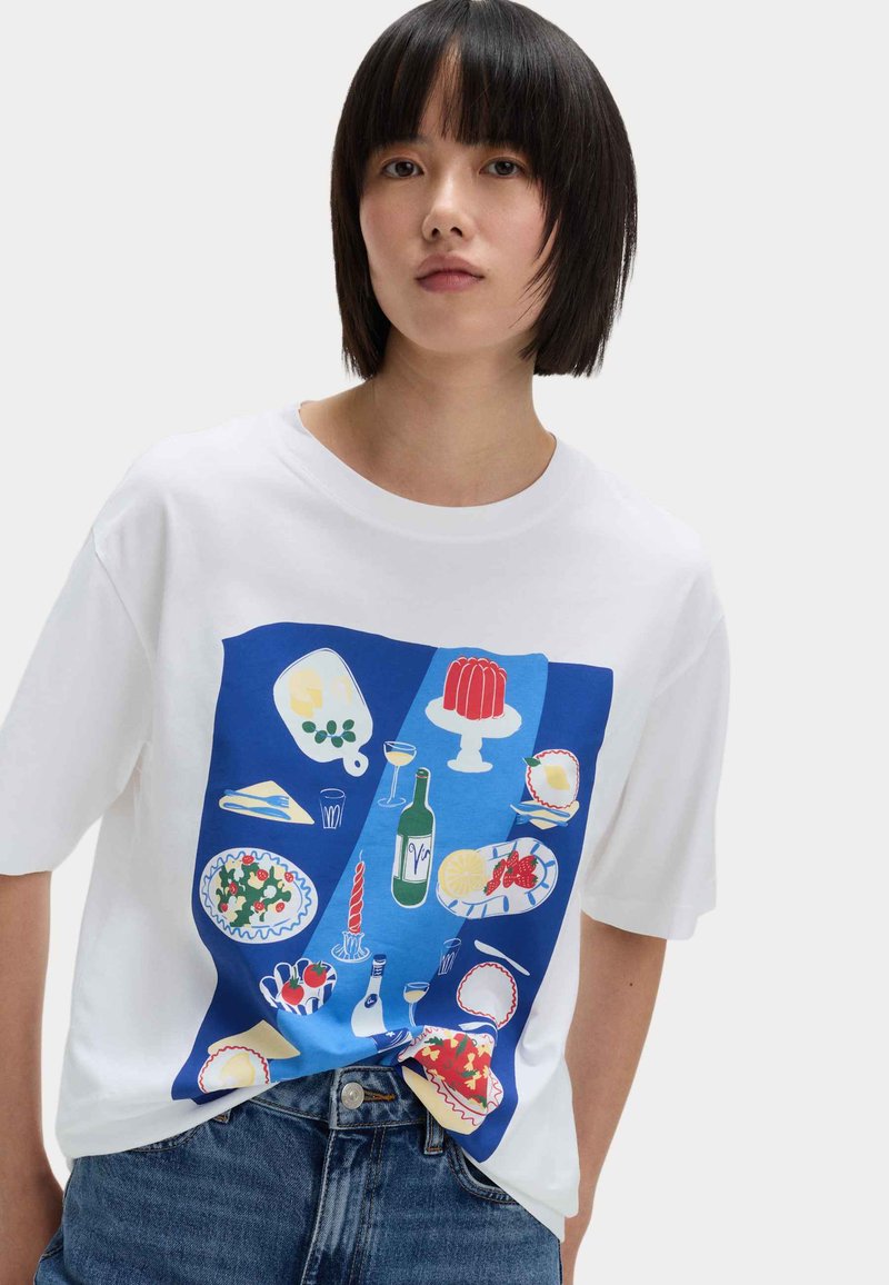 Witte T-shirt met een blauw grafisch ontwerp dat geïllustreerde voedingsmiddelen toont, waaronder een kreeft, jam en een wijnfles, op de voorkant.