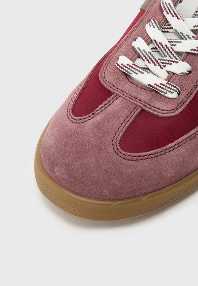 Trampki zamszowe i nylonowe w odcieniach różu i czerwieni, z białymi sznurowadłami w wzór oraz gumową podeszwą w kolorze gumy.