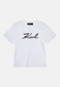 Camiseta de algodón blanca de manga corta, con un logo de lentejuelas negras en forma de escritura "Karl" en el frente y un cuello redondo.