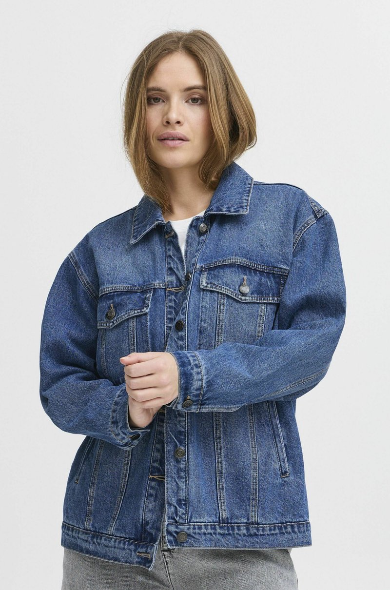 Denim jakna v modri barvi, z dolgimi rokavi, ovratnikom, sprednjimi žepi, gumbi in sproščenim krojem ter mehko teksturo.