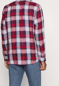 Rood, wit en blauw geruit overhemd met lange mouwen, een button-down kraag en een licht gebogen zoom. Katoenen stof met een gladde textuur.