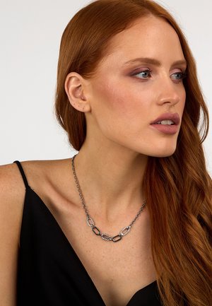 Collana in argento con maglie geometriche alternate, comprensiva di elementi texture e lisci, indossata su una maglietta nera.