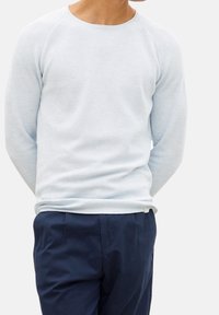 Suéter de manga larga azul claro con un patrón de punto texturizado y un cuello redondo, combinado con pantalones azul oscuro.