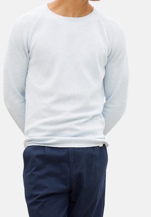 Suéter de manga larga azul claro con un patrón de punto texturizado y un cuello redondo, combinado con pantalones azul oscuro.
