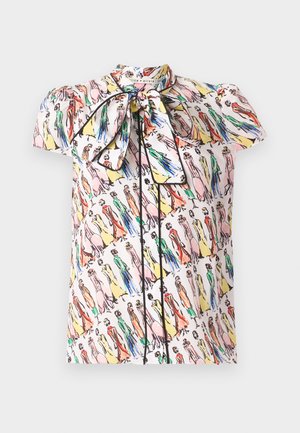 Bluzka z krótkim rękawem z kolorowym, abstrakcyjnym nadrukiem modnej postaci oraz dużą kokardą wiązaną przy szyi na jasnym tle.