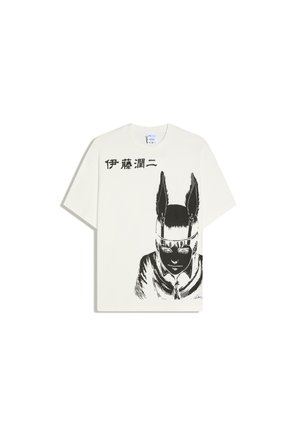 T-shirt blanc avec un dessin noir d'une personne portant un bandeau à plumes et un texte japonais au-dessus du dessin sur le côté gauche.