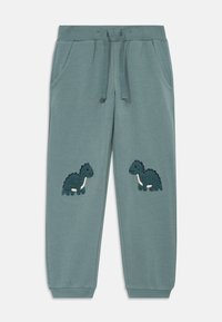 Pantaloni jogger verdi con vita a costine, coulisse e due tasche laterali. Presentano ricami di design di dinosauri su ciascuna gamba.