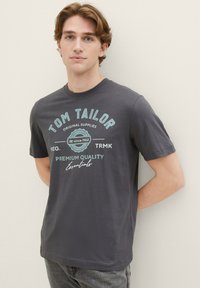 Grå bomulds t-shirt med blå trykt tekst, der siger "TOM TAILOR," "PREMIUM QUALITY," og "Essentials," med rund hals og korte ærmer.