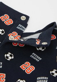 Navy knit fabric with football patterns, featuring the text "FUTURE LEGEND" and the number "28." Snap closure at the collar.