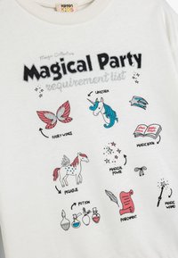 Sudadera blanca con ilustraciones gráficas coloridas de elementos mágicos, incluyendo un unicornio y un pegaso, con texto y acentos brillantes.