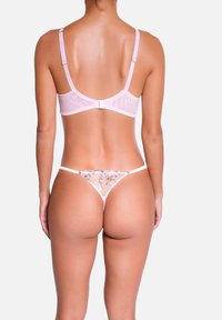 Ensemble de lingerie rose comprenant un soutien-gorge transparent à bretelles ajustables et un string décoratif en dentelle florale avec des détails de broderie complexes.