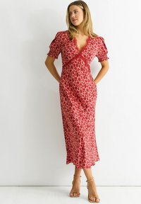 Red floral midi dress with short puff sleeves, deep V-neck, and lace trim. Lightweight fabric with a flowing silhouette and a ruffled hem.