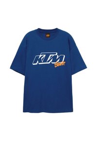Modré bavlněné tričko s oversize střihem, na přední straně s bílým a oranžovým logem "KTM". Kulatý výstřih a krátké rukávy.
