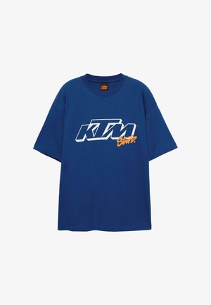 T-shirt in cotone blu con vestibilità oversize, caratterizzata da un logo "KTM" bianco e arancione sul davanti. Collo rotondo e maniche corte.