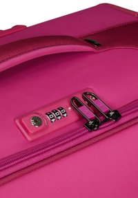 Pink suitcase with a textured surface, side handle, combination lock, and dual zippers. Hardware includes black metal zippers and accents.