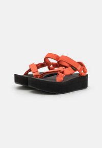 Orange plattformssandaletter med justerbara tygremmar och texturerade svarta sulor. Designen har en lagerkonstruktion och en säker passform.