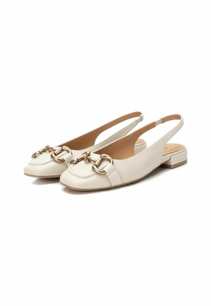Ballerines en cuir beige clair à lanières avec un bout rond, présentant un accent en métal doré à l'avant et un petit talon carré.