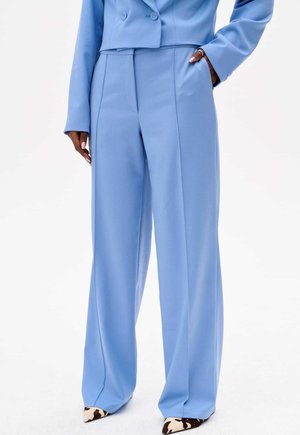 Pantalons larges bleu clair en tissu lisse, avec une taille haute, des poches latérales et une coupe ajustée. Design élégant et minimal.