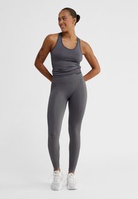 Grå atletisk linne och matchande leggings med en jämn yta. Linnet har en rund halsringning, medan leggingsen har en hög midja.