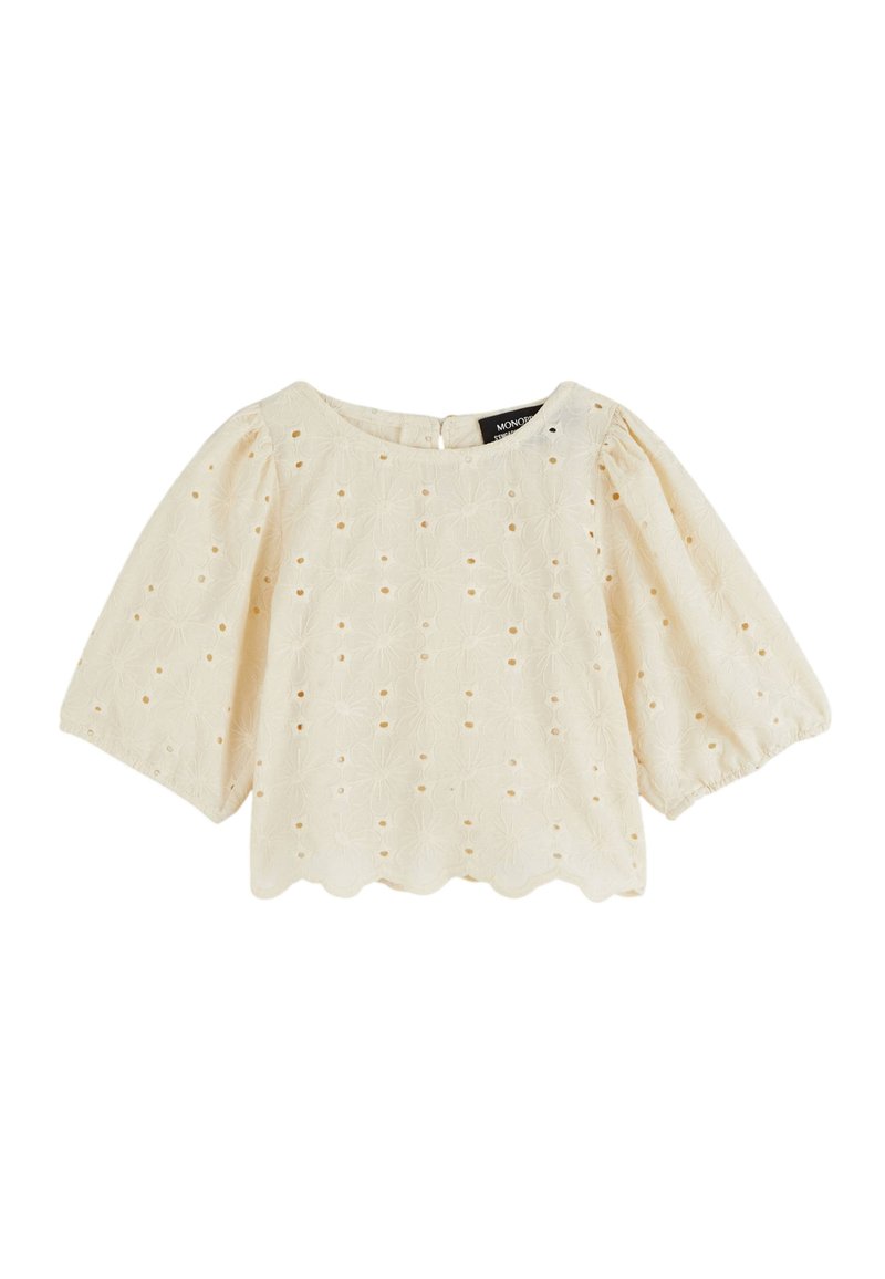 Blouse crème avec des manches courtes bouffantes, motif floral brodé, ourlet festonné et fermeture à bouton au dos.