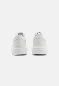 Sneakers bianchi con esterno in pelle liscia, retro imbottito e suola in gomma testurizzata; caratterizzati da sottili accenti blu e un interno foderato.