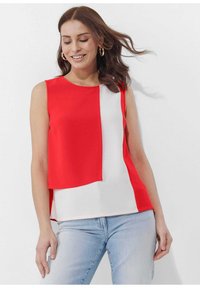 Rood en wit mouwloos topje met een kleurblokontwerp en een ronde halslijn, gemaakt van een gladde stof, gecombineerd met lichtblauwe jeans.