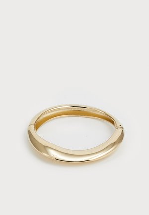 Gullfarget banglesmykke med en jevn, rund design. Har en polert finish og åpen bakside for enkel påføring.