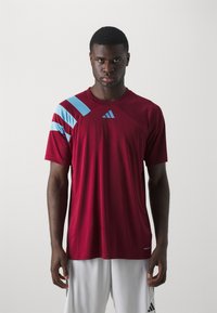 Burgunderfarbenes Sport-T-Shirt mit hellblauen diagonalen Streifen an der Schulter, aus atmungsaktivem Material, mit Rundhalsausschnitt und Logo.
