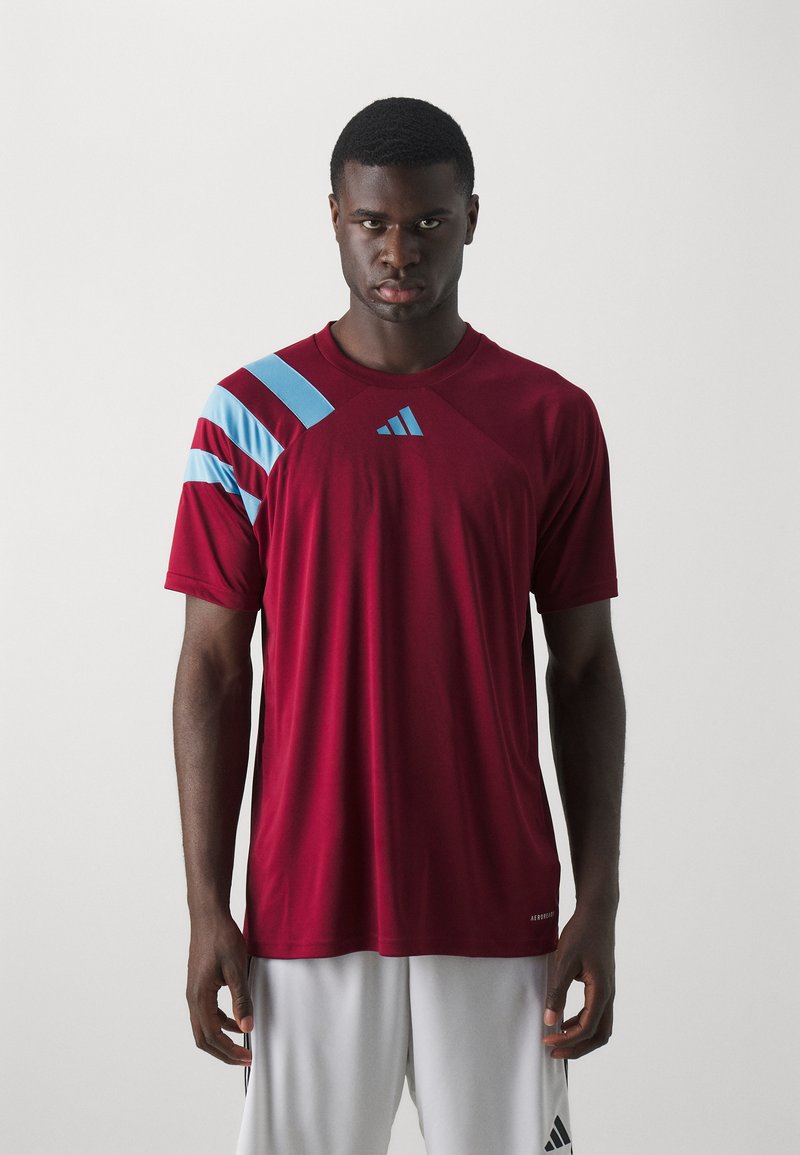 Burgunderfarbenes Sport-T-Shirt mit hellblauen diagonalen Streifen an der Schulter, aus atmungsaktivem Material, mit Rundhalsausschnitt und Logo.