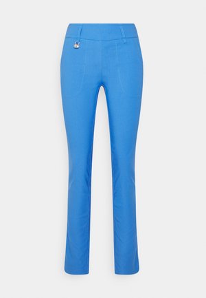 Pantalon bleu vif ajusté avec poches plaquées à l’avant et un petit pendentif métallique accroché près de la taille.