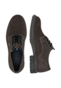 Hnědé semišové boty s černými šňůrkami a strukturovanými gumovými podrážkami. Mají kulatou špičku a kontrastní švy. Obě boty jsou zobrazeny z pohledu shora.