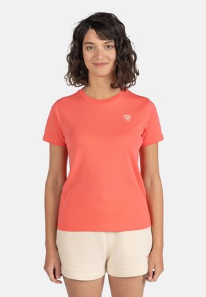 Helle korallenfarbene Kurzarm-T-Shirt mit rundem Halsausschnitt und einem kleinen Logo-Detail auf der linken Brust. Aus glattem, weichem Stoff gefertigt.
