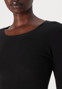 Black long-sleeve top with a rounded neckline, made of soft, lightweight cotton fabric, featuring smooth texture and fitted design.
