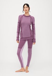 Conjunto de ropa activa en púrpura que incluye una camiseta de manga larga con estampado y leggings ajustados con texturas variadas, rayas y diseños geométricos.