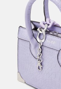 Lilla tekstureret håndtaske med afrundede håndtag, sølvkæde og spændedetalje samt ALDO-logoet på forsiden mod hvid baggrund.