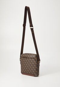 Borsa a tracolla marrone con motivo, dotata di accenti dorati del logo, chiusura con zip e tracolla regolabile. Tessuto testurizzato con rifiniture in pelle.
