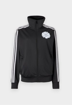 Giacca da allenamento nera con zip e collo alto, strisce bianche lungo le maniche e logo floreale grigio chiaro sul petto. Due tasche laterali.