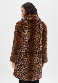 Płaszcz z futerka w panterkę, z szerokim kołnierzem, długimi rękawami i miękką fakturą. Paleta kolorów obejmuje odcienie brązu i beżu.