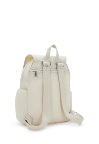 Mochila beige con correas ajustables, bolsillos laterales, un asa superior para llevar y un bolsillo trasero con cremallera, sobre un fondo blanco.