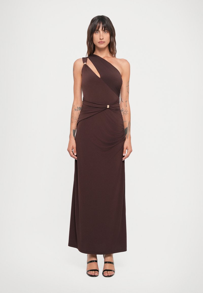 Asymmetrische bruine jurk met één schouder, gedrapeerde stof en een gathered taille detail met metalen accent. Zachte textuur, lang model.
