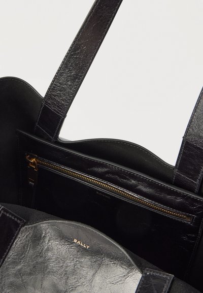 Μαύρη δερμάτινη τσάντα χειρός με διπλούς ιμάντες, εσωτερική τσέπη με φερμουάρ και χρυσό λογότυπο «BALLY» στην εσωτερική επένδυση.