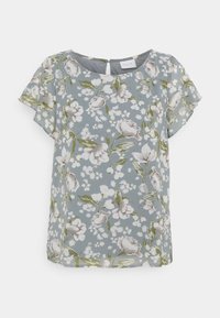 Blus med blommönster i mjukt, lätt tyg. Har rund halsringning, korta ärmar och en blågrå bakgrund med vita och gröna blommor.