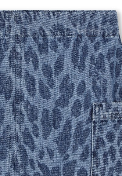 Tissu en denim à motifs léopard dans des teintes de bleu, avec une surface texturée et des détails de couture visibles, incluant un design de poche latérale.
