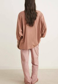 Langsleeve, losse fit, rozenkleurig shirt met een ronde zoom, gecombineerd met brede, lichtroze broeken. Zacht materiaal en een ontspannen silhouet.