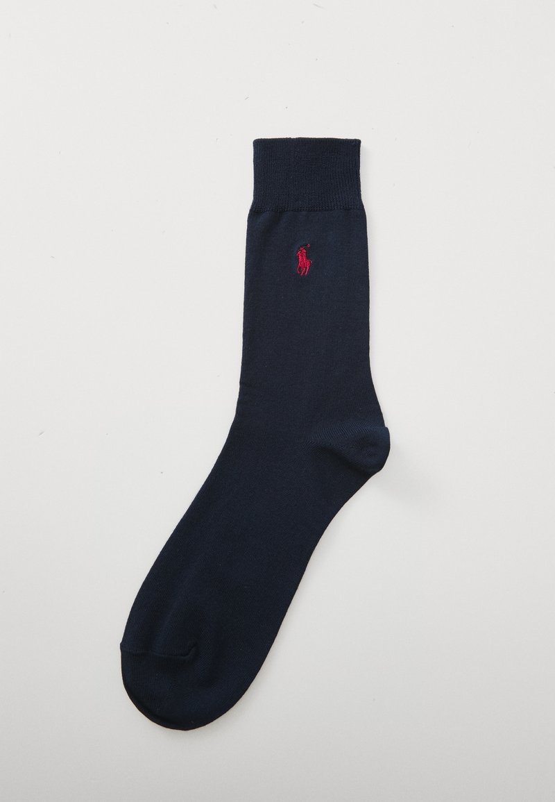 Marinblå strumpa gjord av mjukt tyg med ribbat manschett. Har en liten röd broderad logotyp på sidan. Tjock tå och häla för hållbarhet.