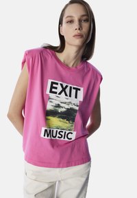 Roze katoenen t-shirt met oversized armsgaten, voorzien van een grafische print van "EXIT MUSIC" en abstracte kunst in zwart en groen aan de voorkant.