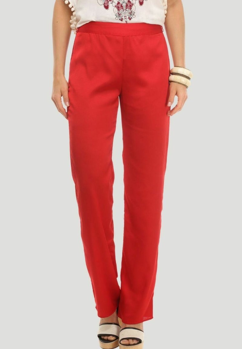 Pantalones rojos de tejido fluido con un corte relajado, que cuentan con una tela suave y una cinturilla ancha. Combinados con sandalias de plataforma y una blusa decorativa.