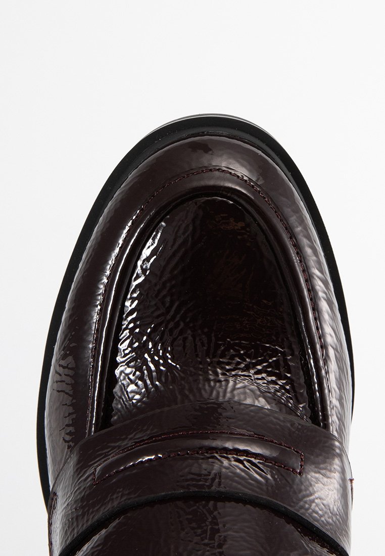 Mocassino in pelle verniciata bordeaux con finitura testurizzata e suola in gomma nera. Il design include un accento di cucitura in rilievo.